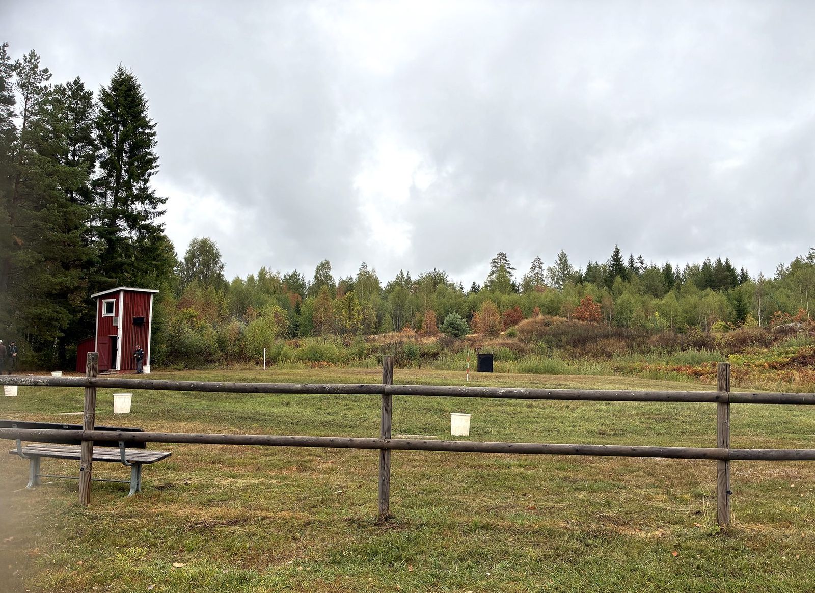 Skjutbanan i Skogstorp med skjuthytt, staket och skogsklädd kulfångsvall.